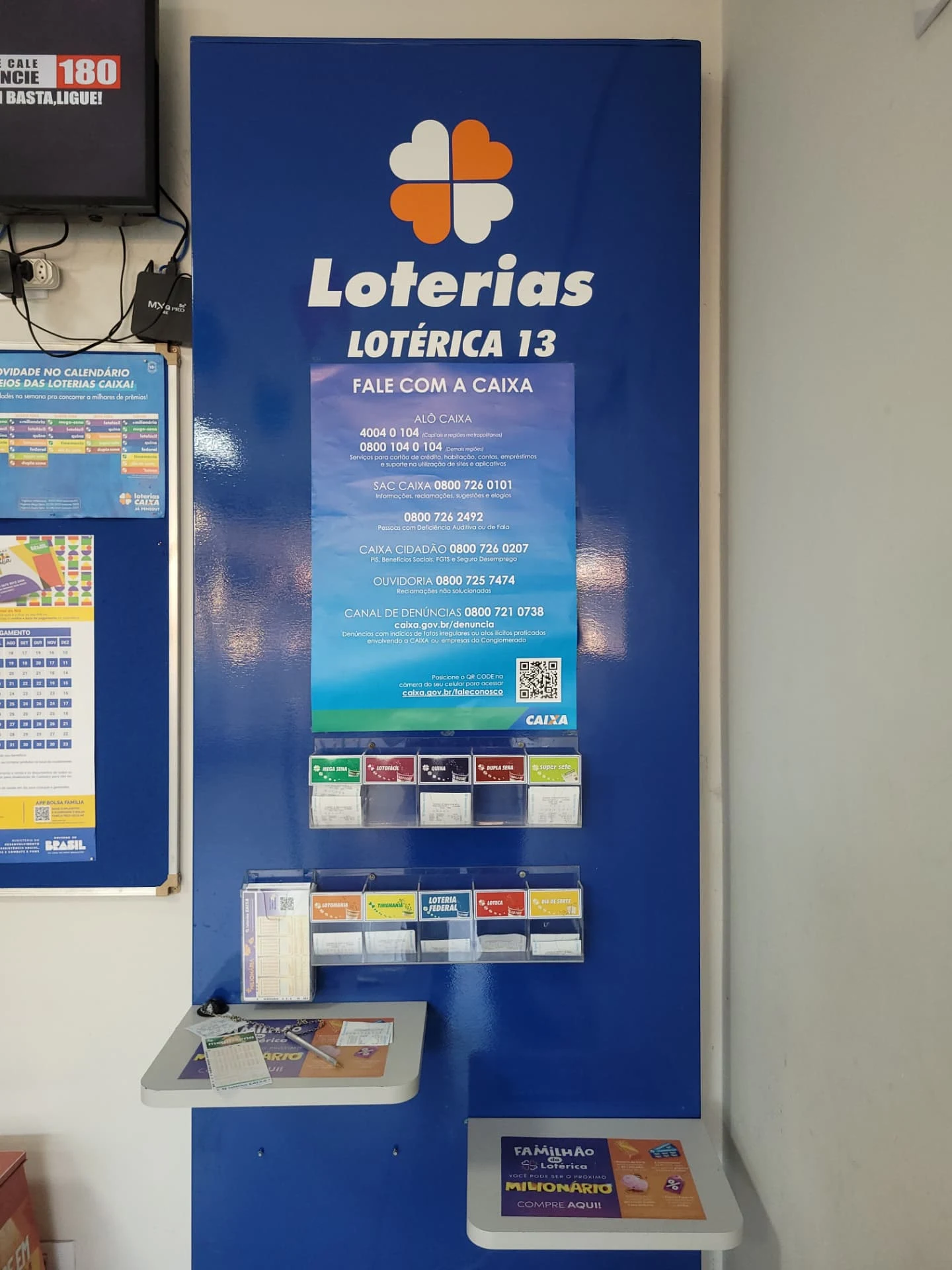 Painel das Loterias Caixa com informações de contato e volantes